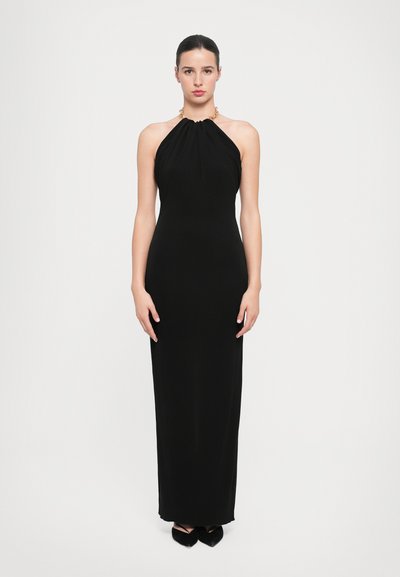 Robe noire à col halter avec un corsage froncé et un accent en chaîne dorée au niveau du col. Silhouette lisse et ajustée qui descend jusqu'au sol.