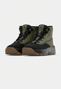 Πράσινα και μαύρα μποτάκια με υφή, που διαθέτουν στιβαρή μαύρη σόλα και αντίθετα κορδόνια με λευκές βουλίτσες. Ανακλαστικές λεπτομέρειες με λογότυπο.