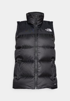 Gilet sans manches matelassé noir avec col haut, zip avant et deux poches latérales. Présente un logo sur le côté supérieur gauche.
