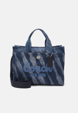 Sac fourre-tout en toile tie-dye bleu avec double poignée, bandoulière amovible et logo brodé "Coach New York" à l'avant. Accents en métal argenté.