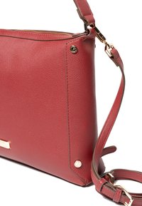 Rote Leder-Umhängetasche mit strukturierter Oberfläche, goldfarbenen Beschlägen, verstellbarem Riemen, Reißverschluss und flachem Boden für Stabilität.