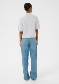 Kerge hallist lõngast kudum, lühikeste varrukatega polo krae ja vabalt istuvad sinised teksad, millel on tagataskud ja õmbluse detailid.