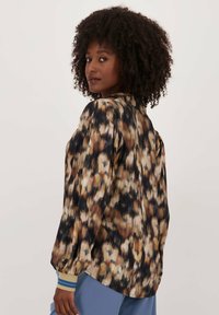 Langermige blouse in een veelkleurig abstract patroon van bruintinten, blauwtinten en zwart. Heeft een relaxte pasvorm en mouwmanchetten met strepen.
