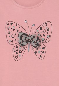 Růžové tričko s velkým grafickým motivem motýla v leopardím vzoru v odstínech šedé a černé, doplněné o odpovídající mašličku.