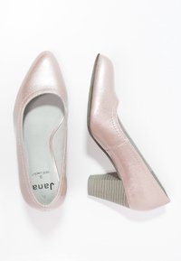 Vaaleanpunaiset metallinhohtoiset korkokengät, joissa on pyöristetty kärki, teksturoitu wedge-korko ja sileä sisävuori. Suunniteltu mukavuutta ajatellen, tiukka istuvuus.