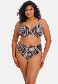 Musta ja tan värvi bikiinide komplekt, kus on rinnahoidjatüüpi topp, millel on lainelised mustrid, laiad rihmad ja kõrge vöökohaga aluspüksid, millel on sobiv disain.