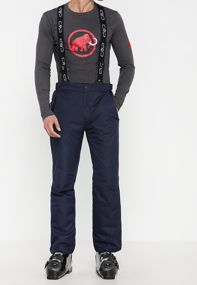Homme portant un pantalon de ski bleu marine avec des bretelles noires, une chemise à manches longues grise avec un logo de mammouth rouge, et des chaussures de ski noires.