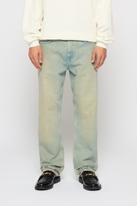 Jean en denim bleu clair avec une coupe droite, design �à 5 poches et texture délavée. Porté avec des mocassins en cuir noir.