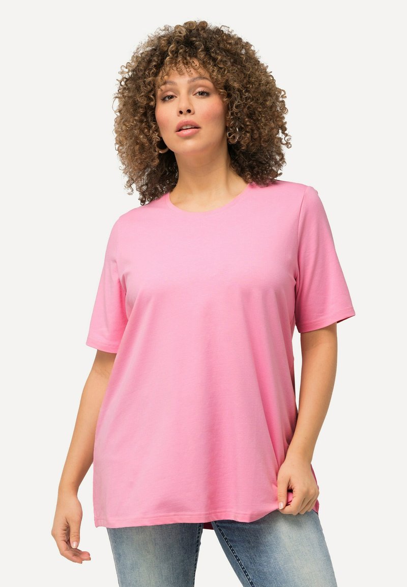 T-shirt in cotone rosa con maniche corte, scollatura rotonda e vestibilità ampia; indossato con jeans in denim azzurro chiaro. Texture liscia, senza motivi.