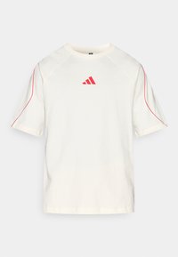 Kremowy t-shirt z krótkimi rękawami, czerwonymi akcentami wzdłuż szwów oraz czerwonym logo Adidas na piersi. Wykonany z miękkiej tkaniny.