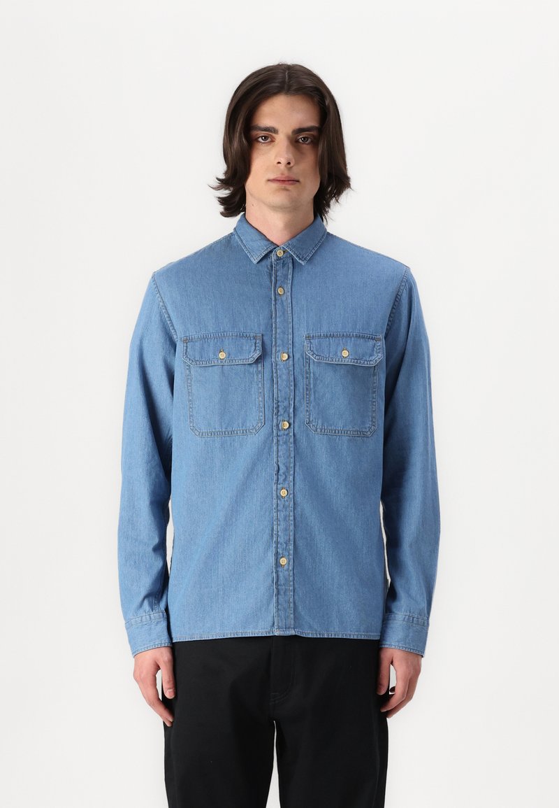 Lichtblauwe denim overhemd met knopen, lange mouwen, twee borstzakken en gouden knopen. Getailleerde pasvorm met een gladde textuur.