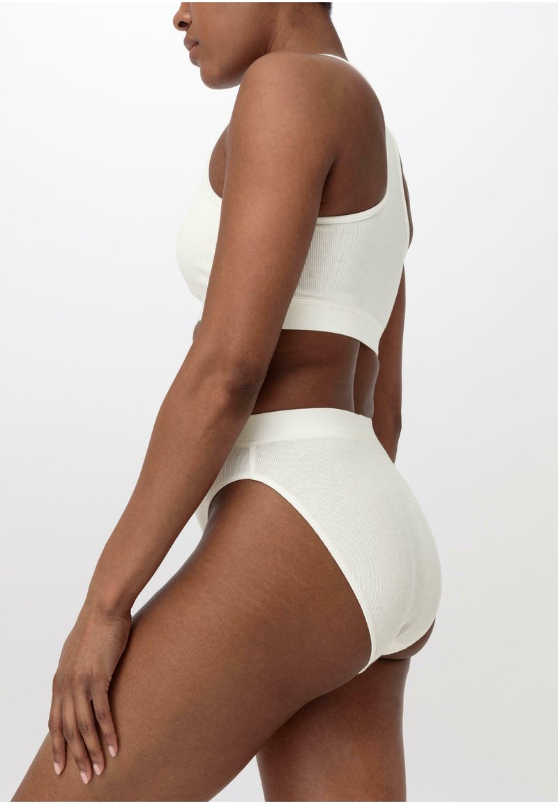 Vitt ribbat bralette och högmidjade underkläder, med sömlös design och mjuk textur, placerad för att visa sidovy.