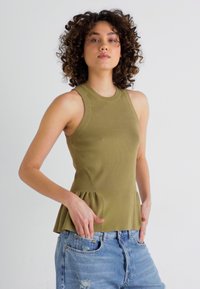 Olive roheline ribadega tank top, millel on kokkuvolditud kehaosa ja peplum alläär. Kombineeritud heledate siniste kulunud teksadega.