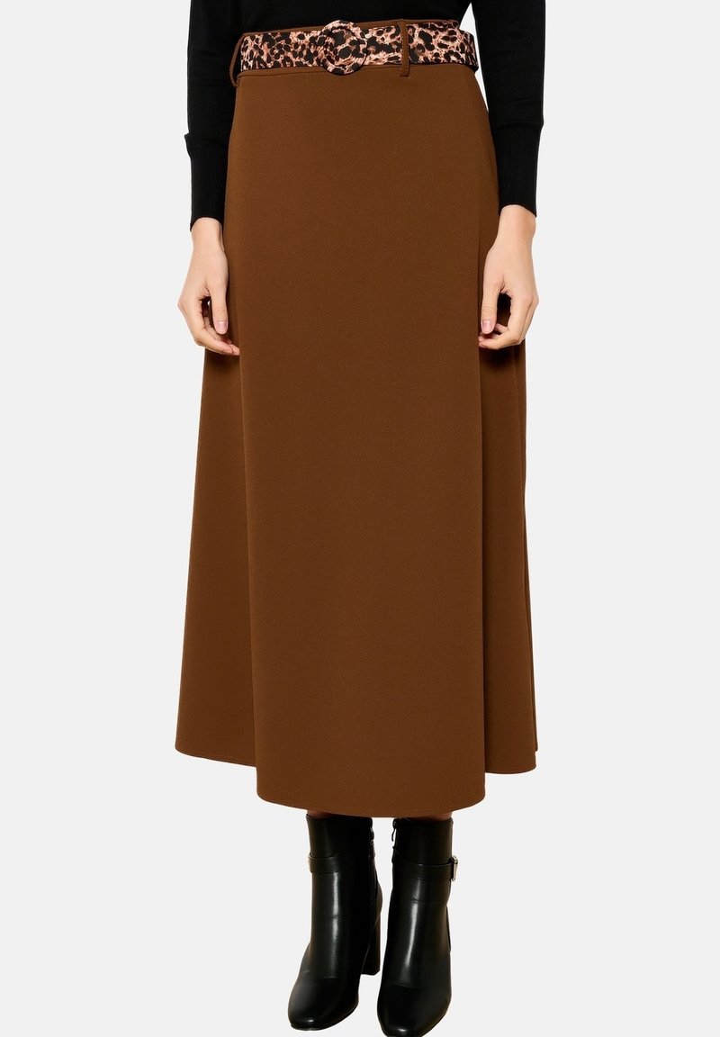 Bruine, vloeiende midilange rok van zacht materiaal, met een riem met luipaardprint. Gecombineerd met zwarte enkellaarzen met hak.