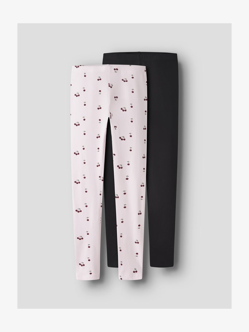 Due paia di leggins per bambini, uno rosa chiaro con stampa di ciliegie, l'altro nero tinta unita, distesi su uno sfondo grigio.