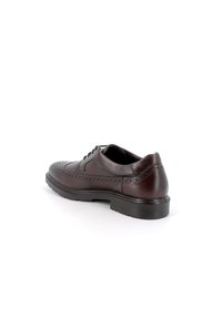 Scarpa da uomo in pelle marrone con dettagli brogue, punta arrotondata e design con lacci. Presenta una suola nera resistente e una texture liscia.
