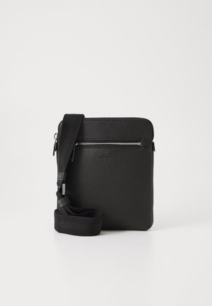 Musta nahkainen ristilaukku, jossa on teksturoitu pinta, vetoketjullinen etutasku ja säädettävä kangasnarukko. Yksinkertainen neliömuoto.