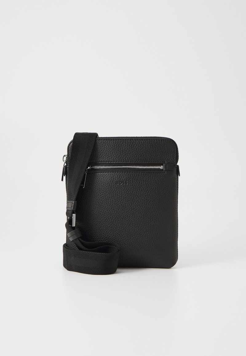 Čierna kožená kabelka na kríž s textúrovaným povrchom, prednou vreckom so zipsom a nastaviteľným látkovým popruhom. Jednoduchý štvorcový dizajn.