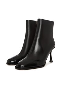Bottines en cuir noir avec un design épuré, une pointe conique et une forme de talon unique. Texture lisse avec une fermeture éclair à l'arrière.
