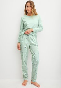 Mintgroene top met lange mouwen en ronde hals; bijpassende pyjamabroek met een patroon van ijsberen op ijs in een vergelijkbare mintkleur.