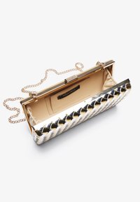 Metallisk vevd clutch-veske med gullramme, kjedehåndtak og beige fôr. Har snap-lukking og innvendig lomme med merkeetikett.