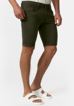 Oliven grønne denimshorts med opkrøllede kanter, som har for- og baglommer. Kombineret med hvide sandaler. Glat, struktureret materiale.