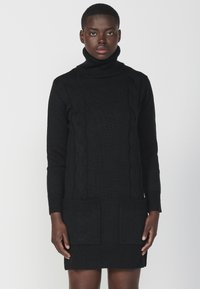 Abito nero in maglia con colletto alto a dolcevita, polsini e orlo a costine, dotato di tasche frontali e motivo a trecce, texture liscia.