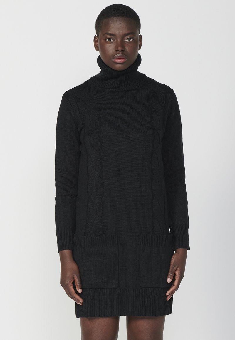 Abito nero in maglia con colletto alto a dolcevita, polsini e orlo a costine, dotato di tasche frontali e motivo a trecce, texture liscia.