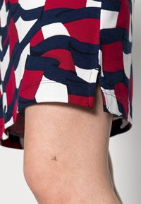 Baumwollrock mit einem wellenförmigen Muster in Rot, Weiß und Marineblau. Seitlicher Schlitz am Saum, der eine glatte Textur und lebendige Farben zeigt.