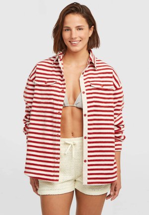 Rdeča in bela flanelska srajca z gumbi in dvema prsna žepa; nošena preko sive bikinke in belih kvačkanih kratkih hlač.