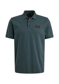 Polo majica u tamnoj tirkiznoj boji, napravljena od pamuka. Ima tri dugmeta na izrezanom dijelu, kratke rukave i malu oznaku logotipa na lijevoj strani grudi.