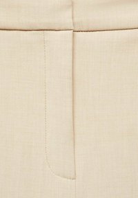 Beige stof met een zachte textuur en subtiele glans. Heeft een platte naad en zijzak met een schoon, minimalistisch ontwerp.