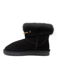Stivale alla caviglia in suede nero con un morbido polsino in pelliccia, caratterizzato da una catena decorativa in tono oro e una suola in gomma testurizzata per una migliore aderenza.