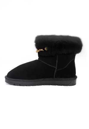 Musta mokkanahka nilkkabooti, jossa on pehmeä turkisreuna, koristeellinen kultasävyinen ketju ja teksturoitu kumipohja gripin vuoksi.