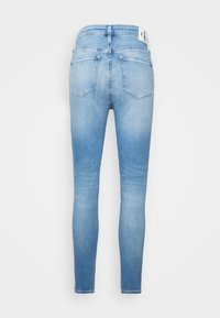 Ljust blå skinny jeans med hög midja, bakfickor och en subtil blekt textur. Har en märkesetikett i midjan.