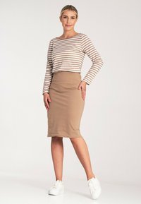 Pasiasty, beżowy sweter z długim rękawem; dopasowana, beżowa spódnica do kolan; zestawione z białymi sneakersami, tworząc swobodną stylizację.