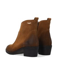Hnědé semišové kotníkové boty s nízkým blokovým podpatkem, hladkou texturou, bočním zipem a malým kovovým akcentem na podpatku.