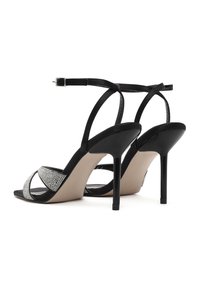 I sandali neri con tacco alto presentano un design a strisce, impreziosito da strass argentati, e una soletta nude liscia.