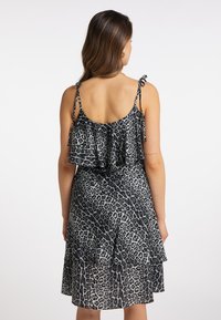 Rochie cu imprimeu leopard negru și gri, cu volane suprapuse, bretele reglabile și o siluetă mulată. Material neted și ușor.