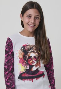 Weißes Langarm-T-Shirt mit einem farbenfrohen Grafikdruck einer Frau in Sonnenbrille. Die Ärmel sind mit pinken Blättern verziert. Aus weichem Baumwollmaterial.