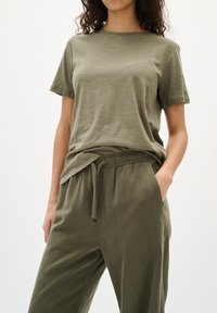 Olijfgroene katoenen T-shirt met een relaxte pasvorm en ronde hals, gecombineerd met bijpassende broek met koord en zijzakken.