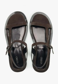 Bruine suède sandalen met een transparante rubberen zool, T-bar ontwerp, verstelbare enkelriem en reliëf merklogo op de binnenzool.