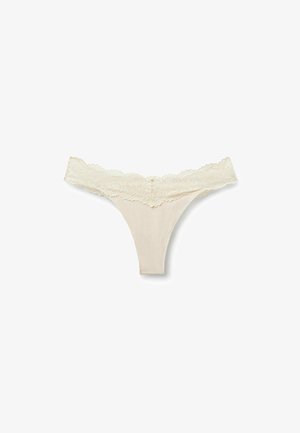 Beige cotton thong with a wide lace waistband featuring floral patterns, laid flat on a white background.