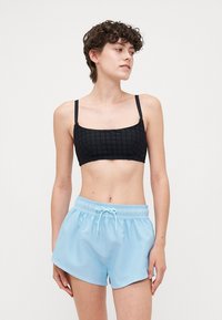 Fekete textúrájú, vékony pántos cropped top, sötétkék, zsinóros fürdőnadrággal párosítva. Mindkét ruhadarab laza szabású és puha anyagból készült.