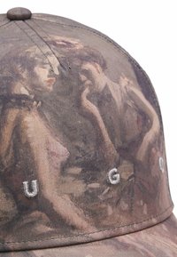 Pet met een gestructureerde, meerkleurige stof met een schilderijontwerp. Geborduurde letters "U G 0" in zilver aan de voorkant. Gebogen rand.