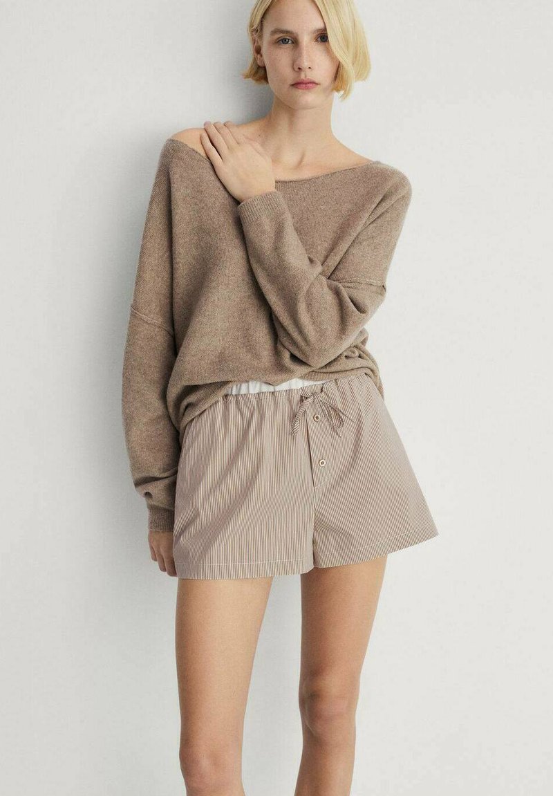 Lichtbruine gebreide trui met verlaagde schouders, gecombineerd met beige gestreepte shorts voorzien van een elastische tailleband en een trekkoordsluiting.