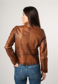 Bruine leren jas met een slim fit ontwerp, zichtbare stiksels en een ronde kraag. Gecombineerd met blauwe denim jeans. Achteraanzicht.