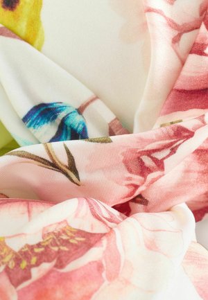 Blommönstrad tyg med stora rosa och blå blommor på en ljus bakgrund. Mjuk textur med draperade veck och subtil glans.