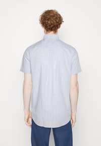Chemise à manches courtes à boutons, en bleu clair et motif vichy blanc, avec un empiècement dans le dos, un ourlet arrondi et un pli simple au dos.