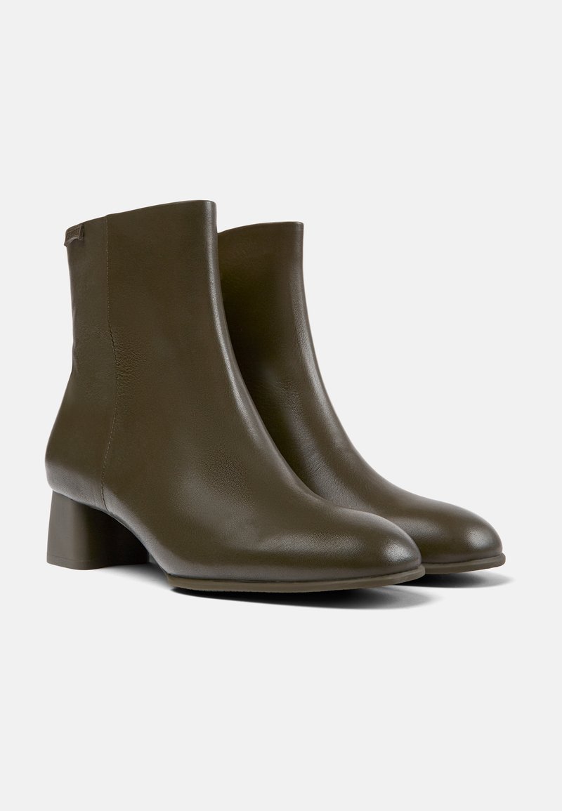 Bottes de cheville en cuir vert olive avec un talon carré, texture lisse et design minimaliste. Embout arrondi et détails de couture subtils.